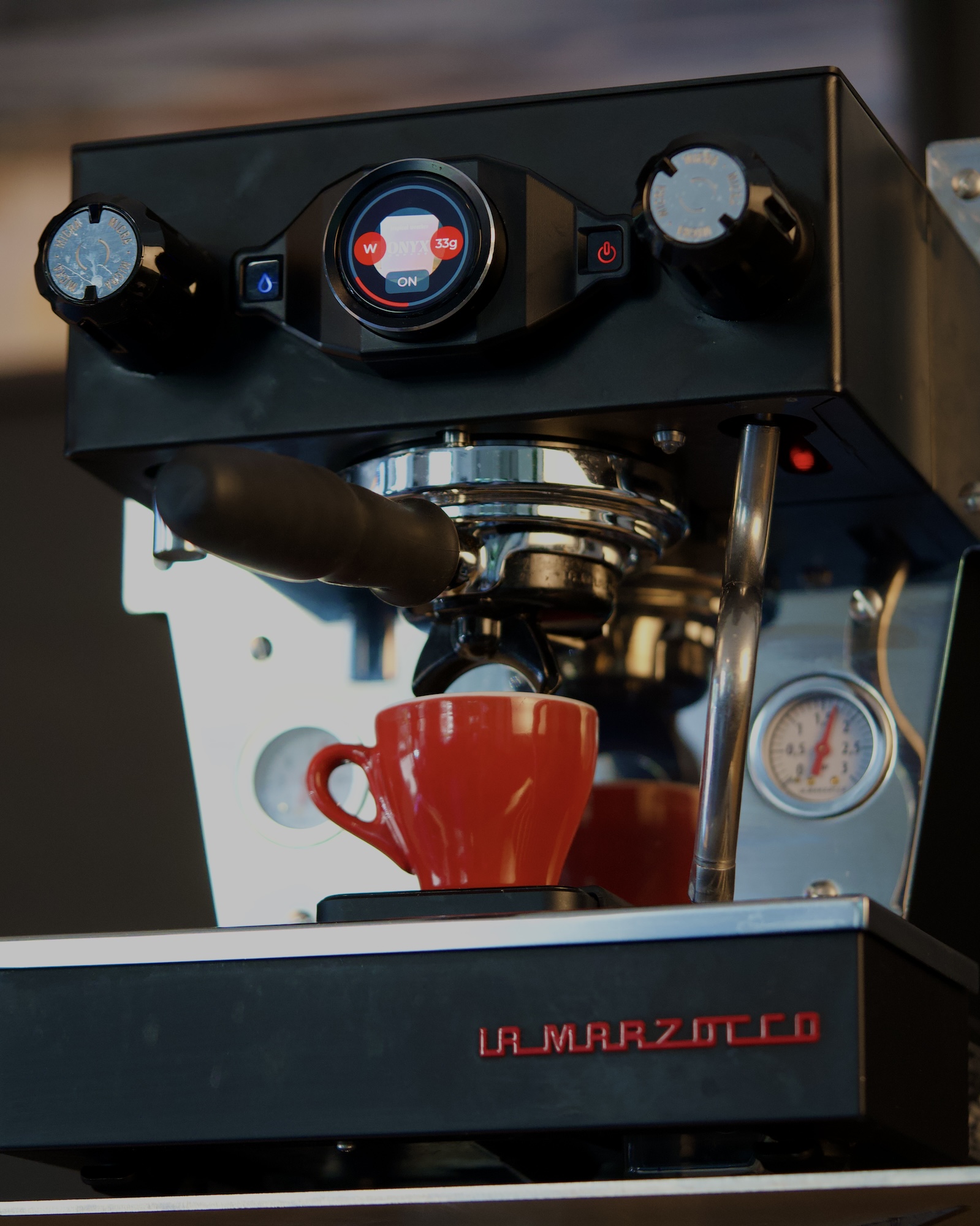 Espresso brewing into a red cup